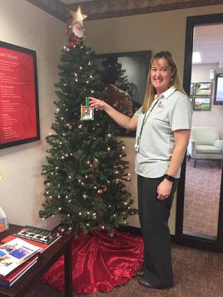 Angie Mills at Administration Office hanging ornament on Christmas tree