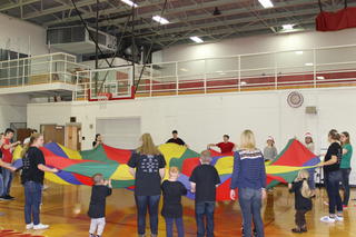 Student Council members and kids playing with parachute game.