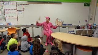 Webster teacher dressed as Pinkalicious book character reading a book with her students.